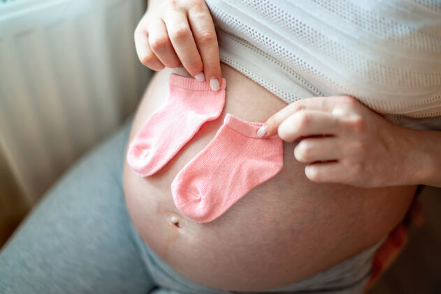 怀孕孕妇光着肚子拿着小袜子床孕妇肚子母亲健康