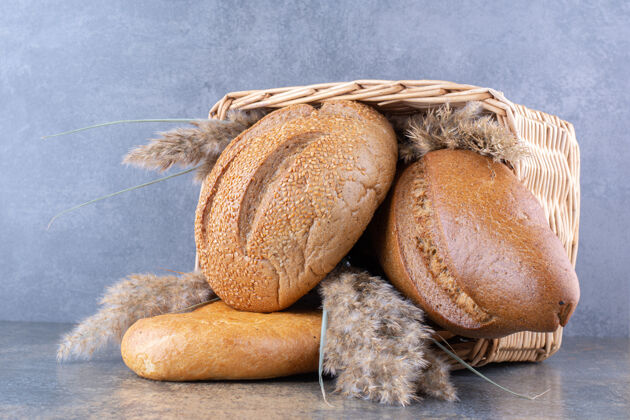 口味装满面包和羽毛草的篮子放在大理石表面面包酵母指挥棒