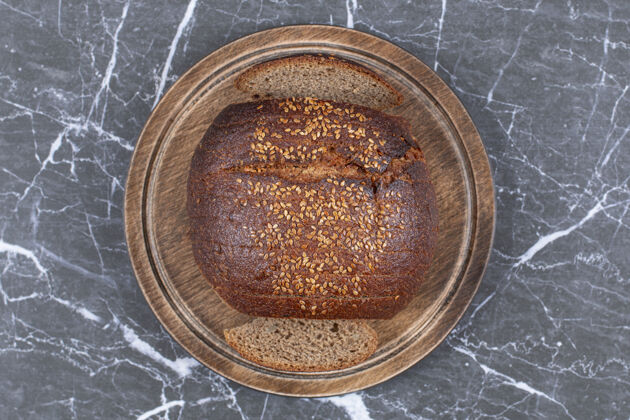 馅料黑面包和芝麻放在木盘上 放在大理石表面芝麻盘子面包