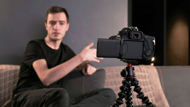 屏幕年轻的内容创作者用三脚架上的相机拍摄自己的照片年轻人播客工作