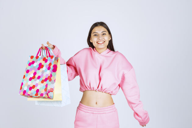 积极女孩拿着五颜六色的购物袋 看起来很兴奋女性姿势服装