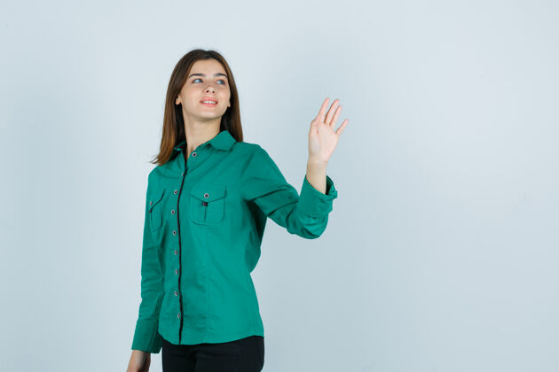 庆典年轻的女性挥手致意 而回首绿色衬衫 看起来快乐 前视图黑发衬衫销售