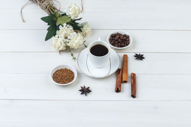 泡沫咖啡在一个杯子里与咖啡豆 香料 鲜花 研磨咖啡高角度看在木制背景上厨房自然早餐