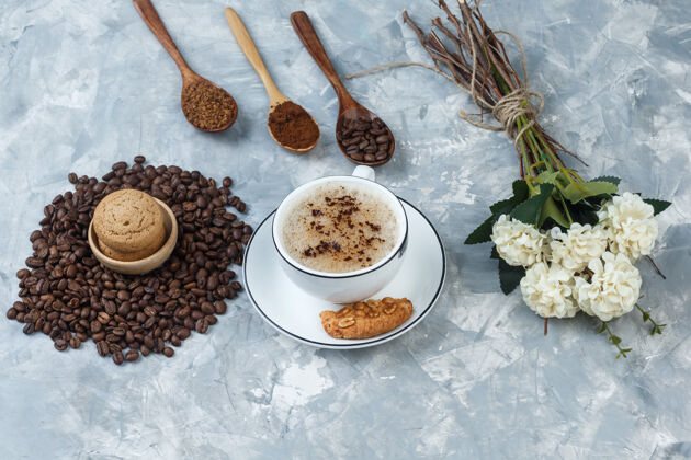 拿铁高角度观看咖啡杯与饼干 咖啡豆 研磨咖啡 花在肮脏的灰色背景水平豆子乡村的卡布奇诺