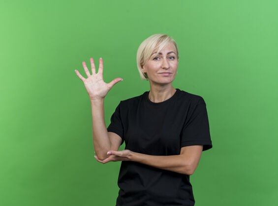 肘自信的中年金发斯拉夫女人 手放在手肘上 展示五只手 手被隔离在绿色墙壁上 有复制空间斯拉夫人女人秀