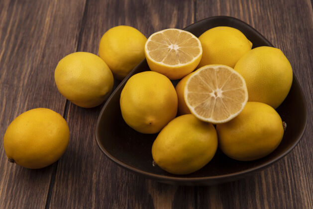 饮食顶视图新鲜的半个和整个柠檬在一个碗柠檬孤立在一个木制的表面柠檬营养木材