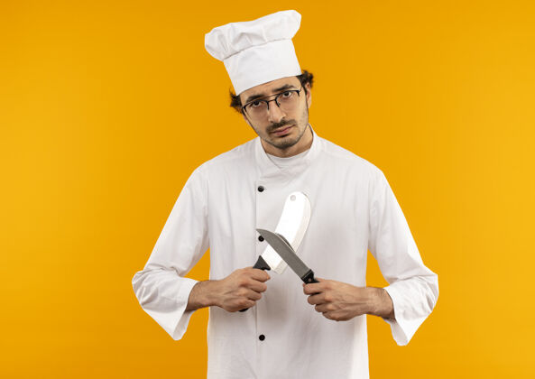 切肉刀年轻的男厨师穿着厨师制服和眼镜锋利的切肉刀和刀烹饪穿制服