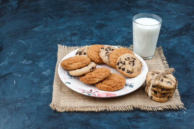 食物不同类型的饼干 牛奶放在深蓝色背景的垫子上高角度视图类型糕点早餐