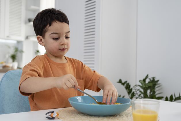 黑人可爱的小男孩吃早餐的画像餐桌勺子果汁