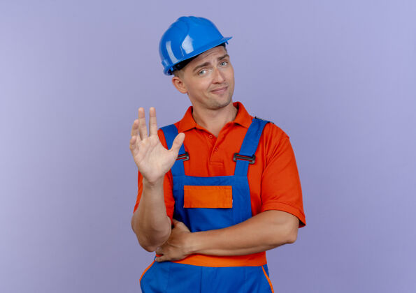 印象令人印象深刻的年轻男子建设者穿着制服和安全帽举手男性建筑工人穿着