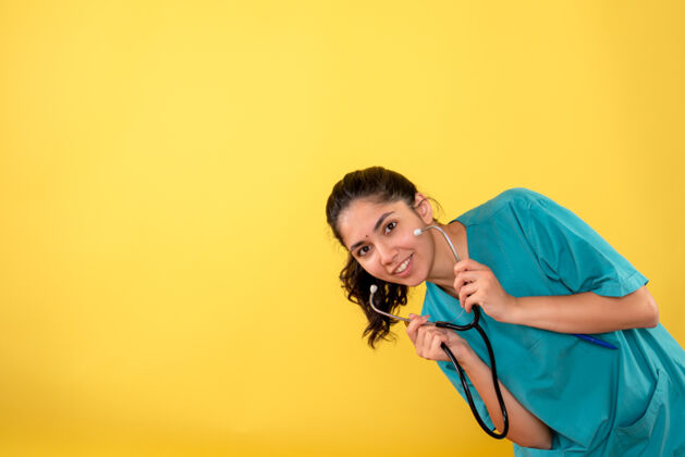 背景正面图微笑的年轻女医生手持听诊器在黄色背景上听诊器微笑肖像
