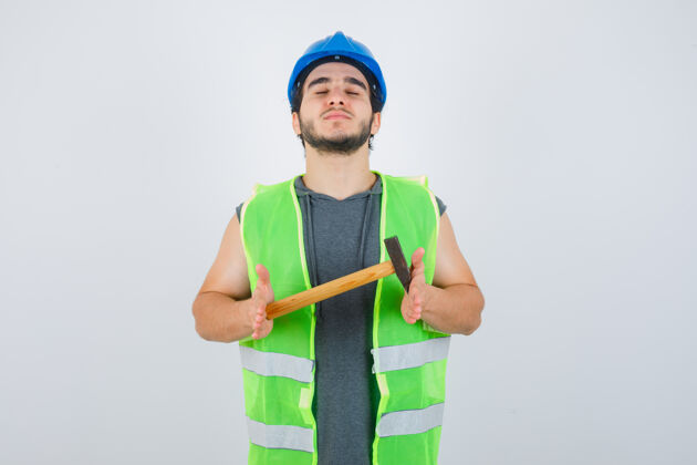 时尚年轻的建筑工人拿着锤子闭上眼睛 穿着工作服 看上去很自信头发眼睛封闭