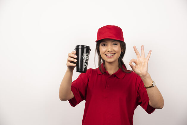 咖啡穿着红色制服的女人在白色背景上展示一杯咖啡年轻人工人成人