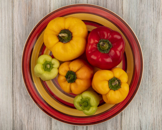 饮食新鲜五颜六色的甜椒在一个灰色的木制表面盘子顶视图蔬菜木头配料
