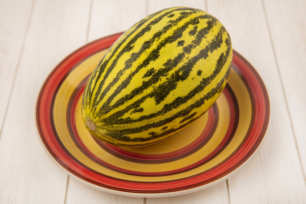 健康新鲜美味的哈密瓜在一个白色的木制表面盘子上俯瞰哈密瓜木头饮食