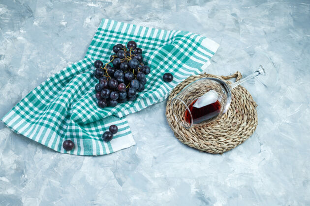 多汁一些黑葡萄和一杯葡萄酒 在石膏和厨房毛巾的背景 平放垫垫饮食玻璃美味