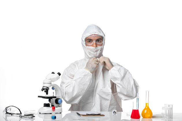 专业正面图：男医生穿着防护服 戴着面罩 因为科维德坐在白色空间里病毒西装面罩