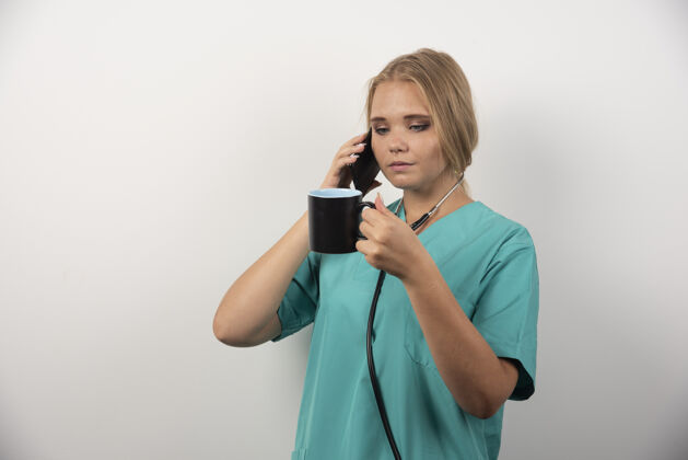 制服女医生一边喝茶一边打电话职业电话听诊器