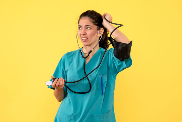 奇迹正面图：身着制服的女医生手持血压计站在黄色背景上背景制服健康