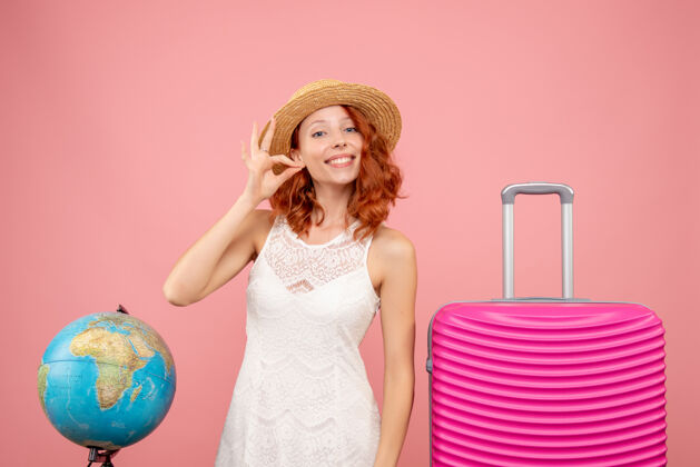 航行年轻女性游客的正面图 浅粉色的墙上挂着粉色的包包夏天旅行