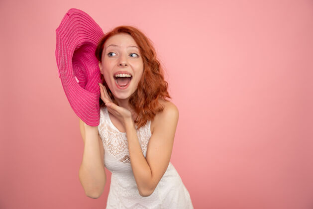 帽子粉红色墙上戴着粉红色帽子的年轻女性的正面图女人前面旅行