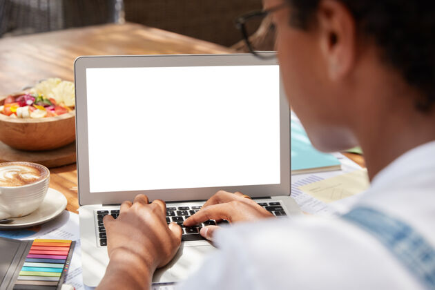 笔记本电脑无法辨认的黑皮肤女子键盘上的笔记本电脑与空白屏幕区域的广告内容女士网站墙壁