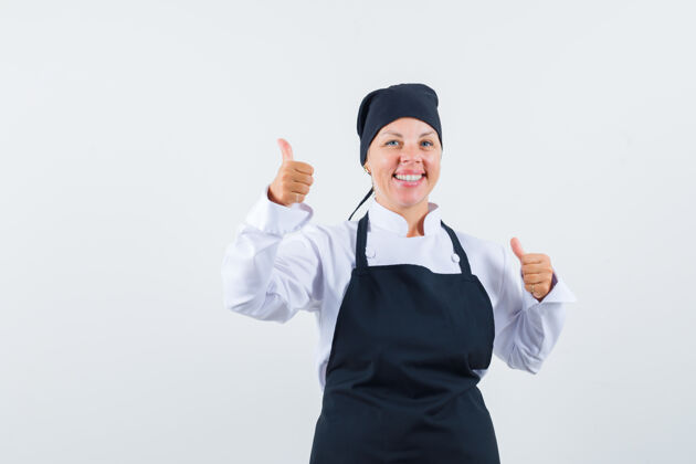 女性身着制服的女厨师 围裙上竖起大拇指 看上去很高兴 正面照卷发美女时尚
