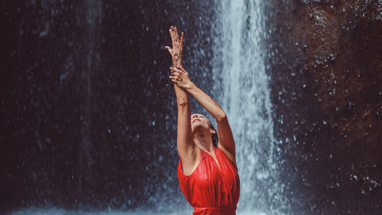 金发穿红裙子的女孩在瀑布里跳舞时尚芭蕾舞女人