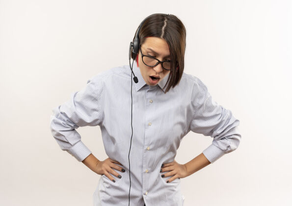 耳机印象深刻的年轻呼叫中心的女孩戴着眼镜和耳机把手放在腰上看着白色的副本空间隔离下空间复制