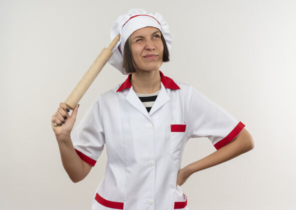 烹饪迷茫的年轻女厨师穿着厨师制服 手里拿着擀面杖 手放在腰上 孤零零地看着白色制服手厨师