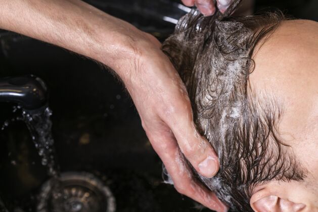 护理给客户洗头的男人专业美容发型师