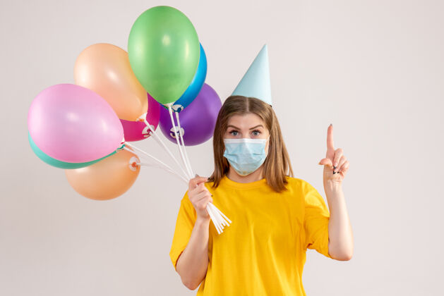 消毒年轻的女性手持彩色气球 戴着白色的无菌口罩面具气球健康