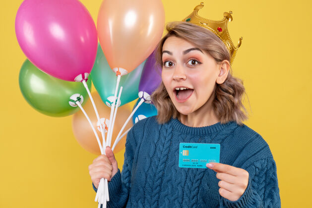 银行手持气球和黄色银行卡的年轻女性庆祝视图圣诞节