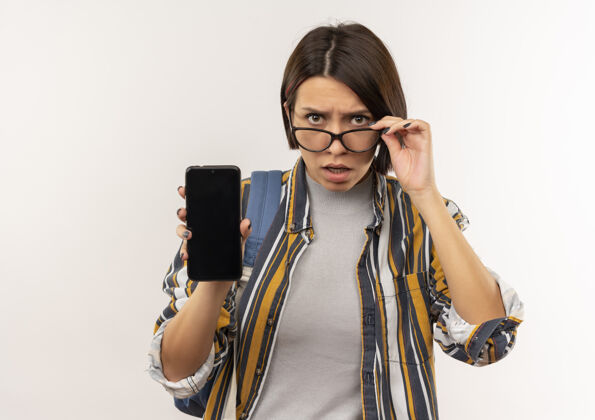 电话迷茫的年轻女学生戴着眼镜 背着书包 手机拿着眼镜 隔离在白色的空白处显示背女孩