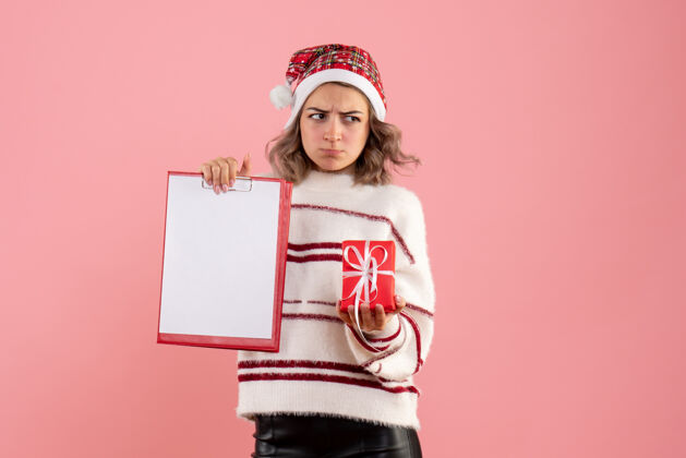 礼物年轻的女性拿着小圣诞礼物和粉红色的纸条圣诞节情感粉色