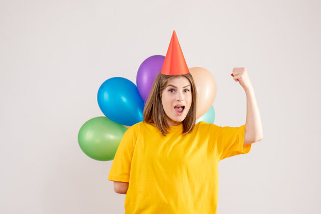 气球年轻的女性把彩色的气球藏在白色的背上视图乐趣背部