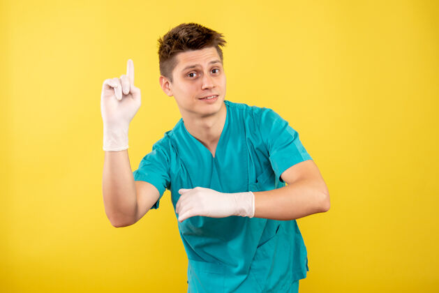 西装正面图：年轻的男医生穿着医疗服 戴着黄色背景的手套男人病毒医学