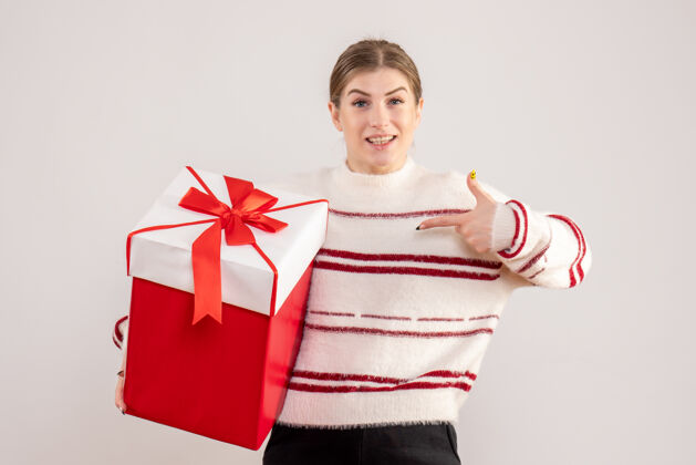 圣诞节年轻的女性拿着白色的红色礼物举行红色情感