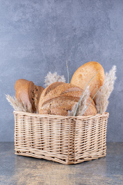 面包装满面包和羽毛草的篮子放在大理石表面烘焙食品羽毛面团