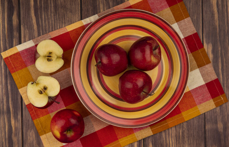苹果新鲜的红苹果在格子布盘子上的俯视图 半个苹果被隔离在木墙上新鲜水果视图
