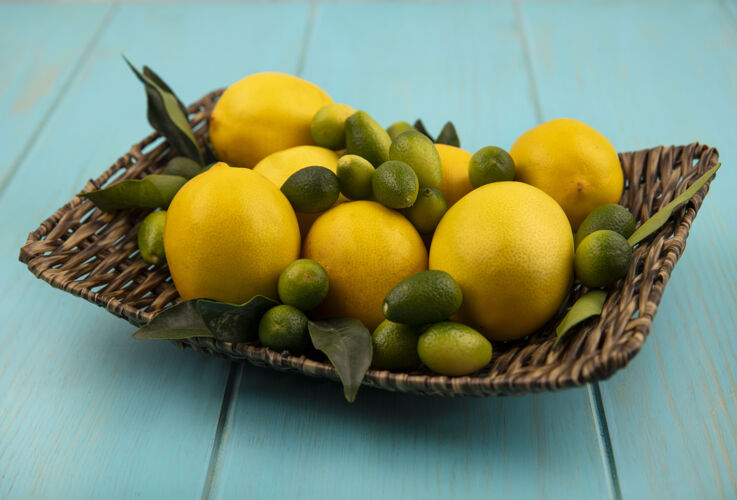 托盘蓝色木墙上柳条托盘上新鲜水果的俯视图 如金盏花和柠檬景观食物人