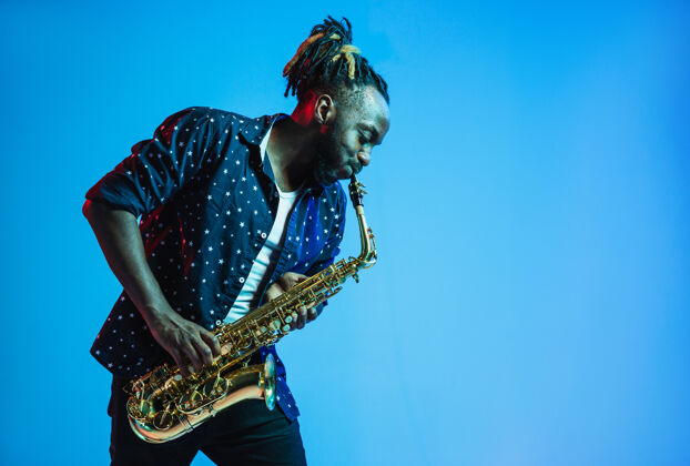酷年轻的非洲裔美国爵士乐音乐家在蓝色的舞台上演奏萨克斯管乐器旋律著名