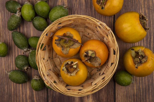 新鲜新鲜柿子水果在木桶上的俯视图 在木墙上隔离着飞珠柿子木头食物