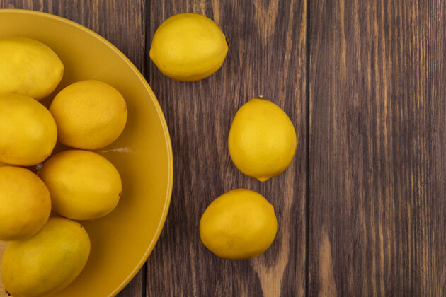盘子新鲜的黄色皮肤柠檬在一个黄色的板上的木制墙壁与复制空间顶视图木头块水果