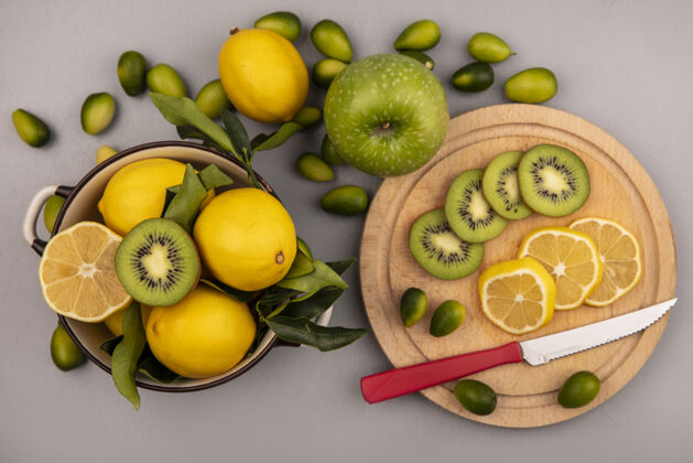 厨房顶视图新鲜的柠檬放在碗里 猕猴桃和柠檬片放在木制的厨房板上 刀子上有金盏花和苹果 隔离在白色的墙上木头顶部苹果