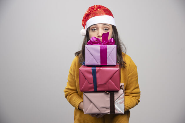 女性微笑的戴着圣诞帽的女人手里拿着礼品盒人冬天表情
