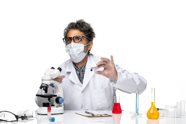 外套正面图身穿白色医疗服的中年科学家正在通过显微镜检查小样本前医学小