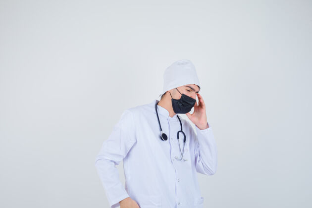 头痛年轻人头痛 身穿白色制服 戴着口罩 表情痛苦正面图爆发制服医疗