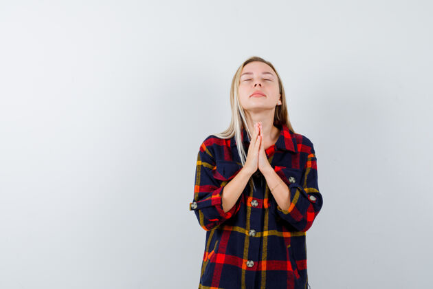 自然年轻女士穿着格子衬衫站着祈祷 看上去很平静正视图衬衫魅力人