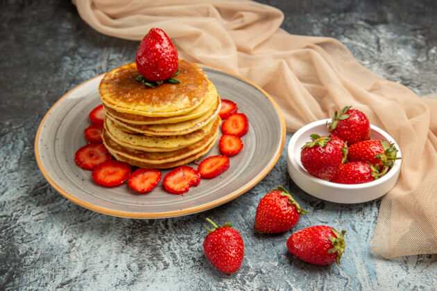 美味正面图：美味的薄煎饼 表面有新鲜的草莓和甜甜的水果蛋糕食物水果覆盆子